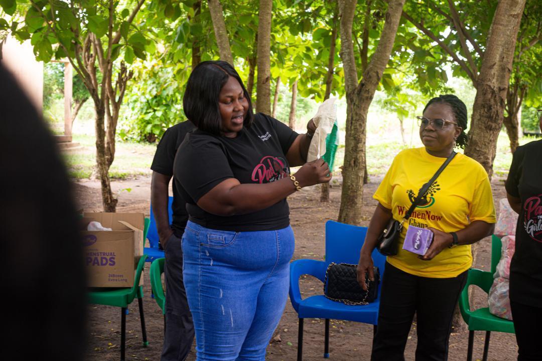 A facilitator demonstrating a menstrual pad beside a WomenNow volunteer